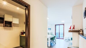 A modern kitchen with wooden cabinets and a dining area with a table and chairs. - Lovely apartment for 4 people with A/C, WIFI, TV and terrace (Giustino)