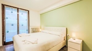 A bedroom with a bed, a nightstand, a radiator, and a window with curtains. - Lovely apartment for 4 people with A/C, WIFI, TV and terrace (Giustino)