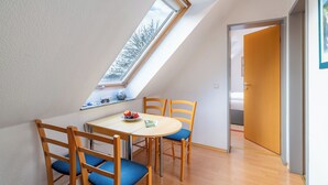 A dining area with a skylight, wooden chairs, a table, and a bowl of fruit. - House Dünenwald 11 - small, cozy domicile with balcony (Zinnowitz)
