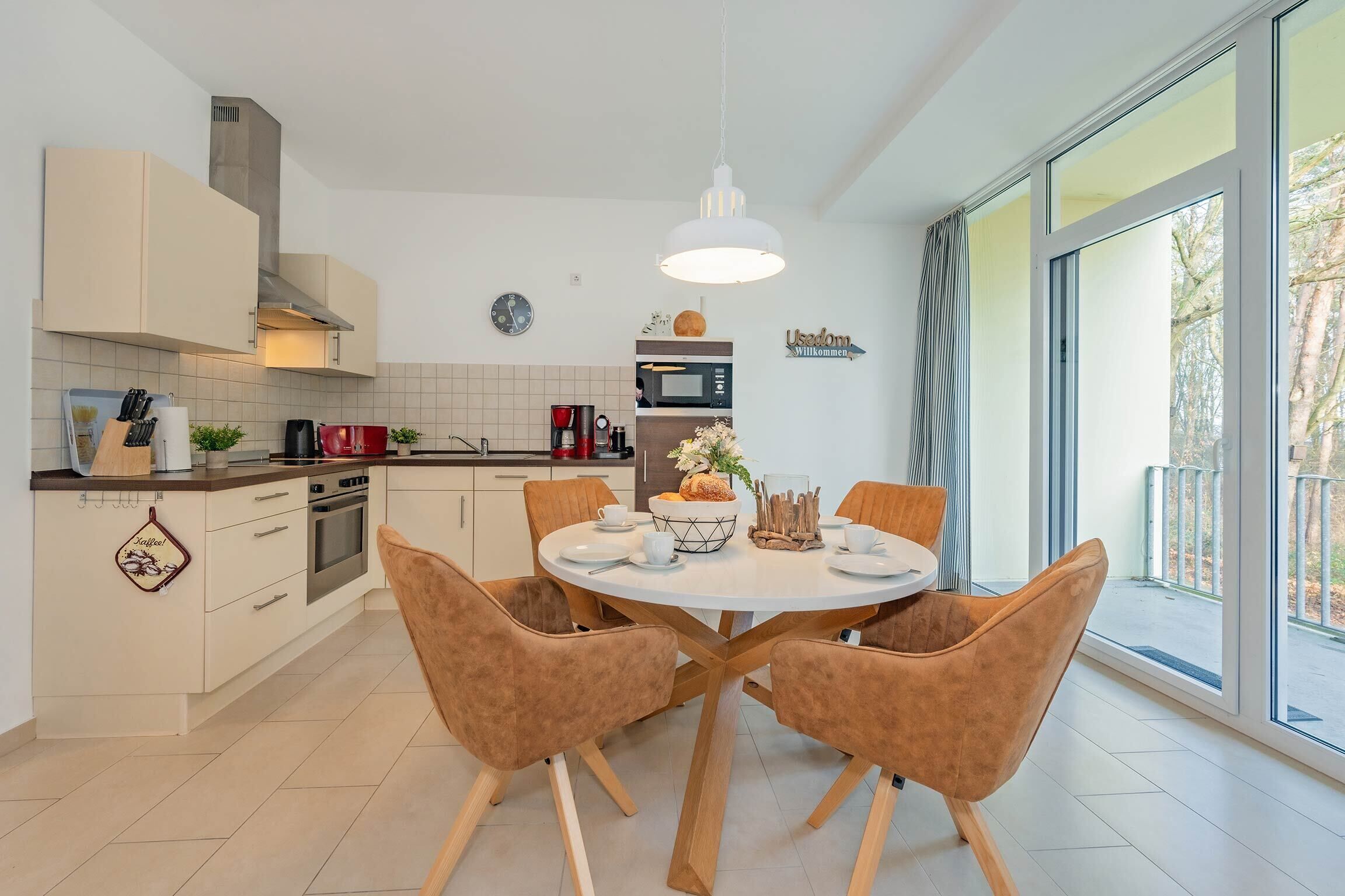 Une cuisine moderne avec des meubles blancs, un îlot central et un coin repas équipé de quatre chaises.