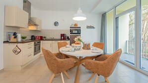 Een moderne keuken met witte kasten, een centraal eiland en een eetgedeelte met vier stoelen.