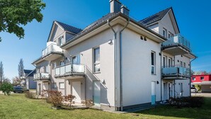Un immeuble résidentiel à deux étages, doté de balcons, d’un garage et d’une pelouse bien entretenue.