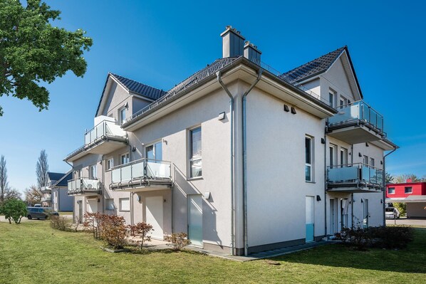 Un immeuble résidentiel à deux étages, doté de balcons, d’un garage et d’une pelouse bien entretenue.