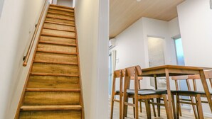 A wooden staircase leading to a dining area with wooden chairs and a table. - TE HOUSE Osaka-Tennoji (Osaka)