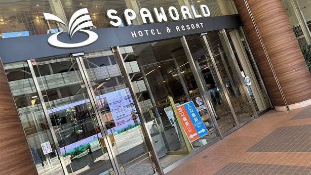 The SPAWORLD HOTEL & RESORT entrance with glass doors, a logo above the entrance, and directional signs for exits and entrances. - TE HOUSE Osaka-Tennoji (Osaka)