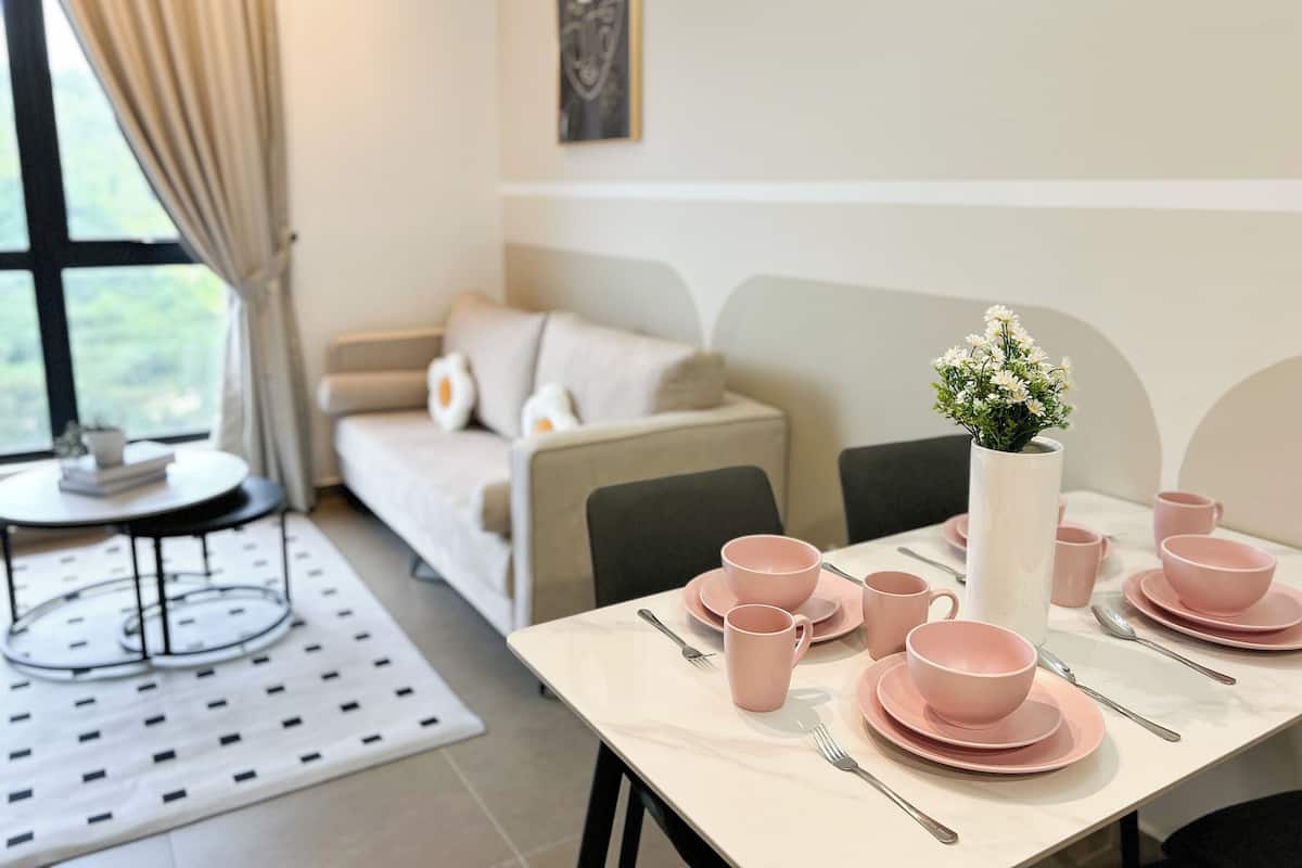 A neatly arranged dining area with pink tableware and a vase of flowers.