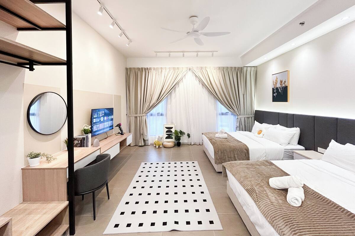 A modern hotel room with a bed, a desk with a computer, a chair, and a large window with curtains.