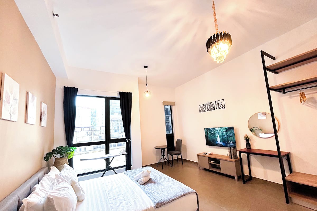 A bedroom with a bed, a TV, a desk, and a chair.