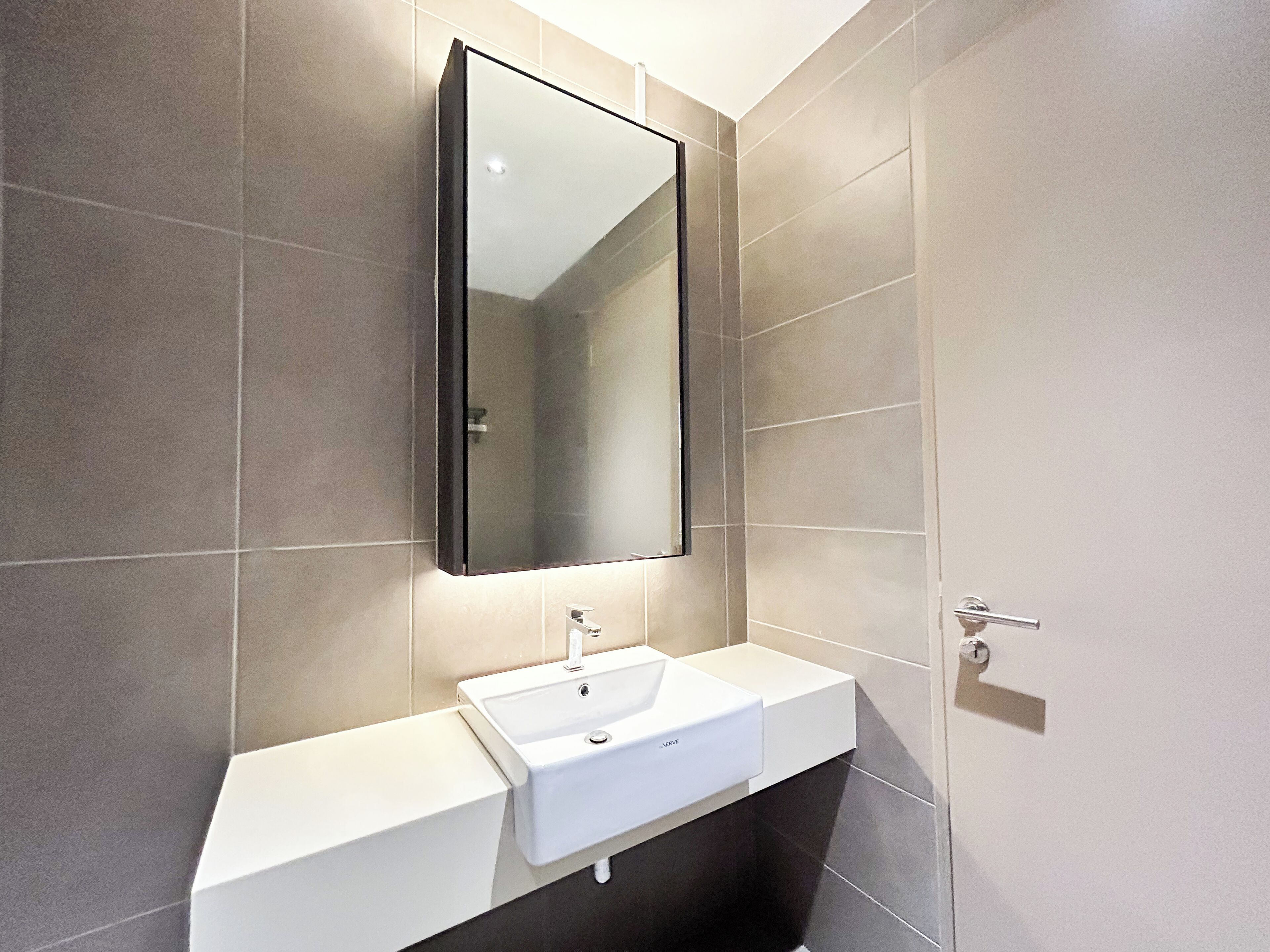 A modern bathroom with a white sink, a mirror, and tiled walls.