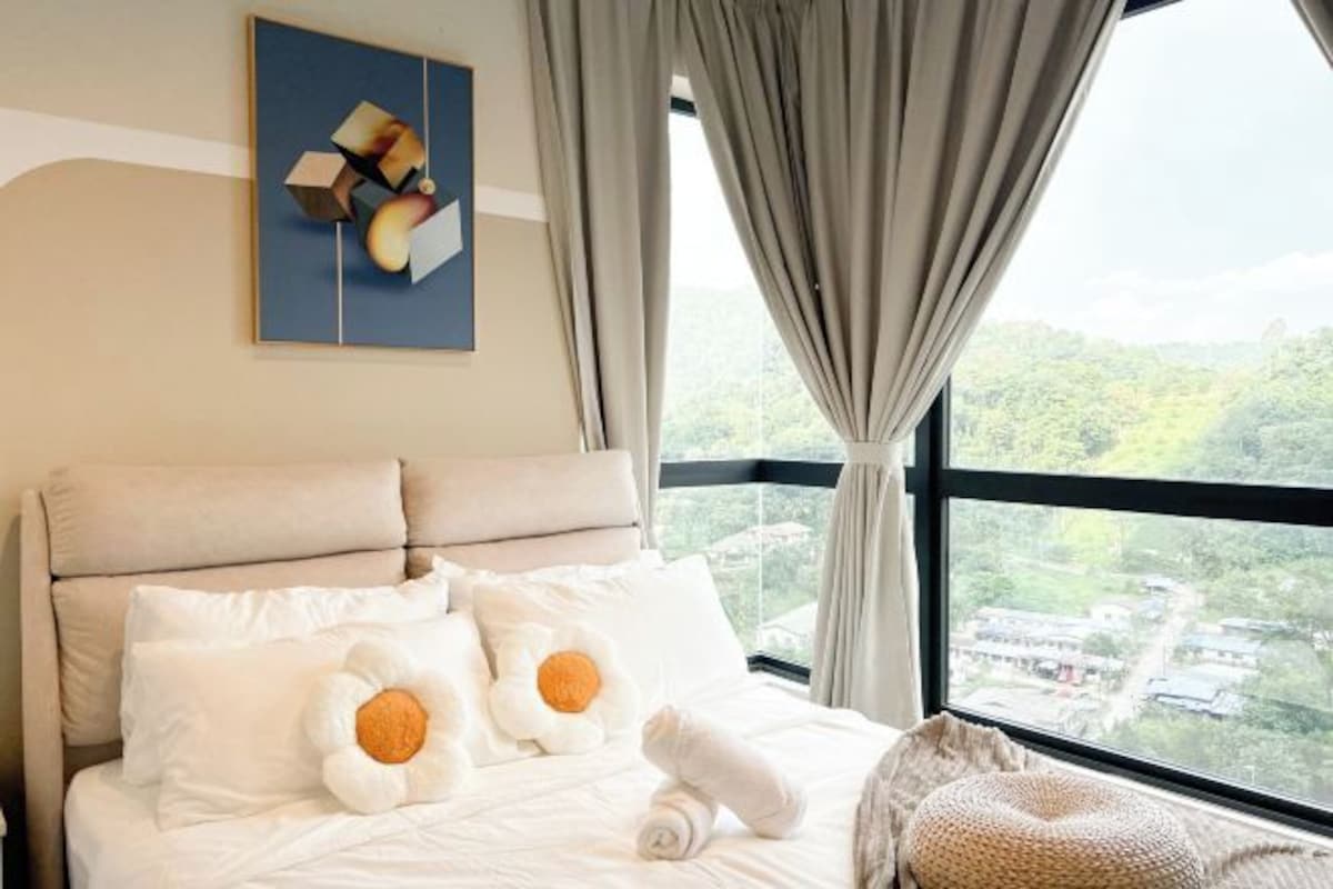 Une chambre d’hôtel avec un lit, des oreillers, une vue sur un paysage par la fenêtre et un tableau au mur.