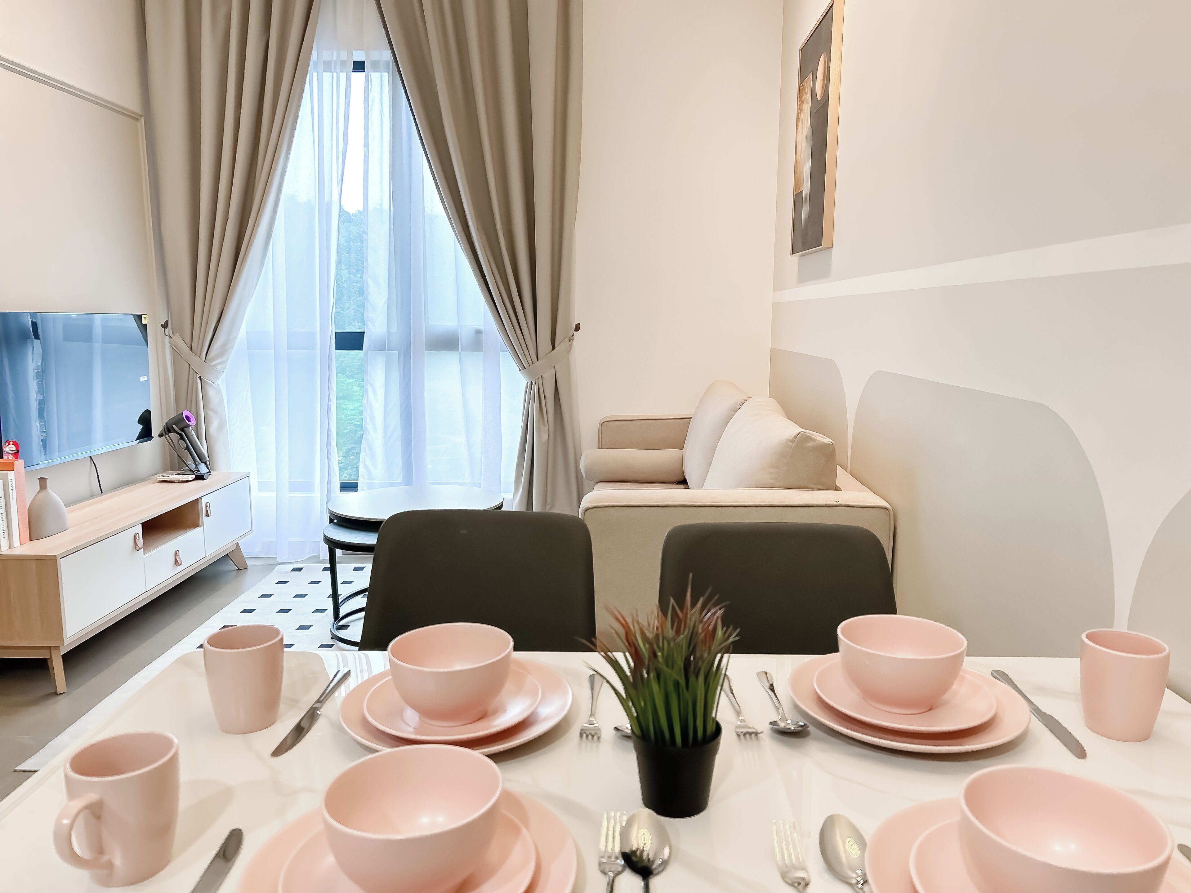 A modern living room with a sofa, a dining table set for two, and a TV on a stand.