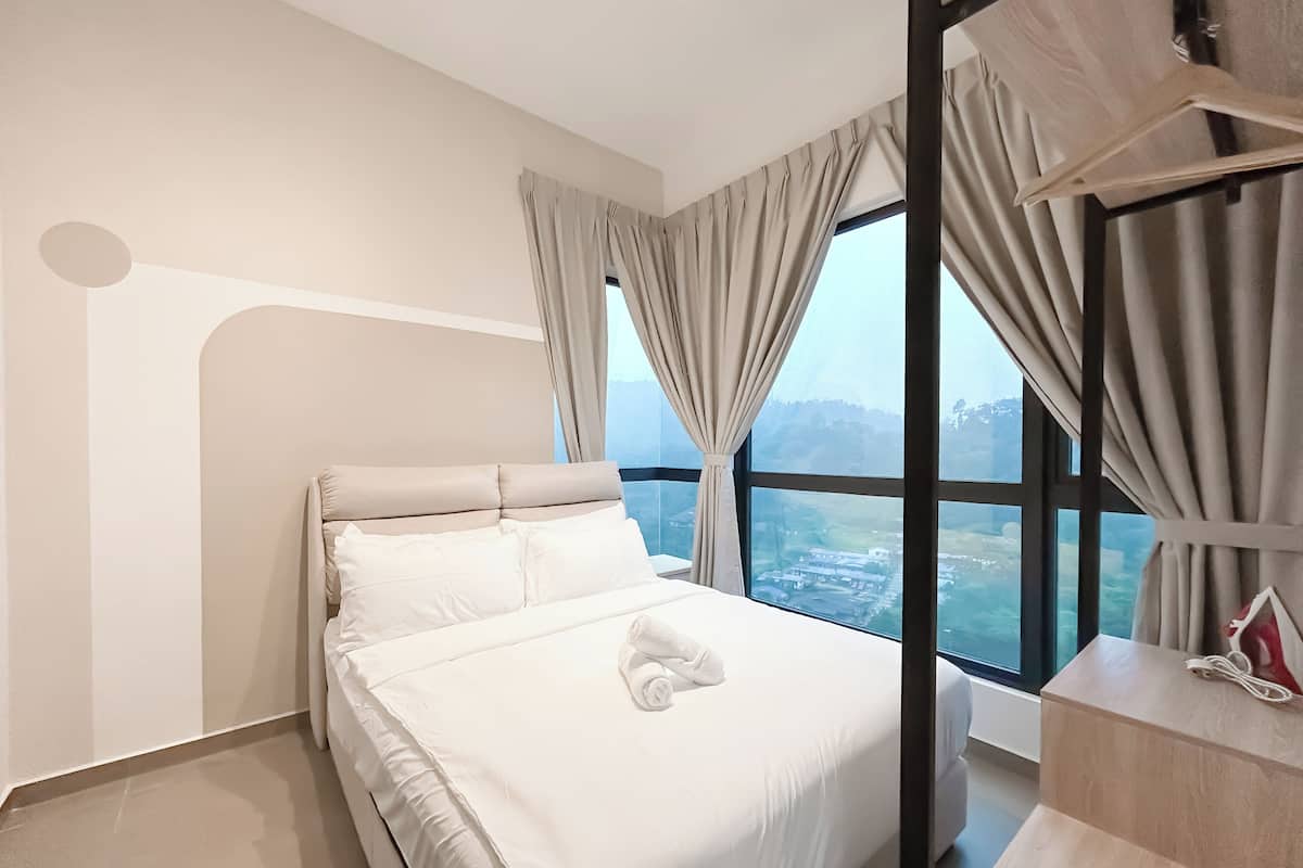 A modern hotel room with a large bed, a view of the city, and a wooden nightstand.
