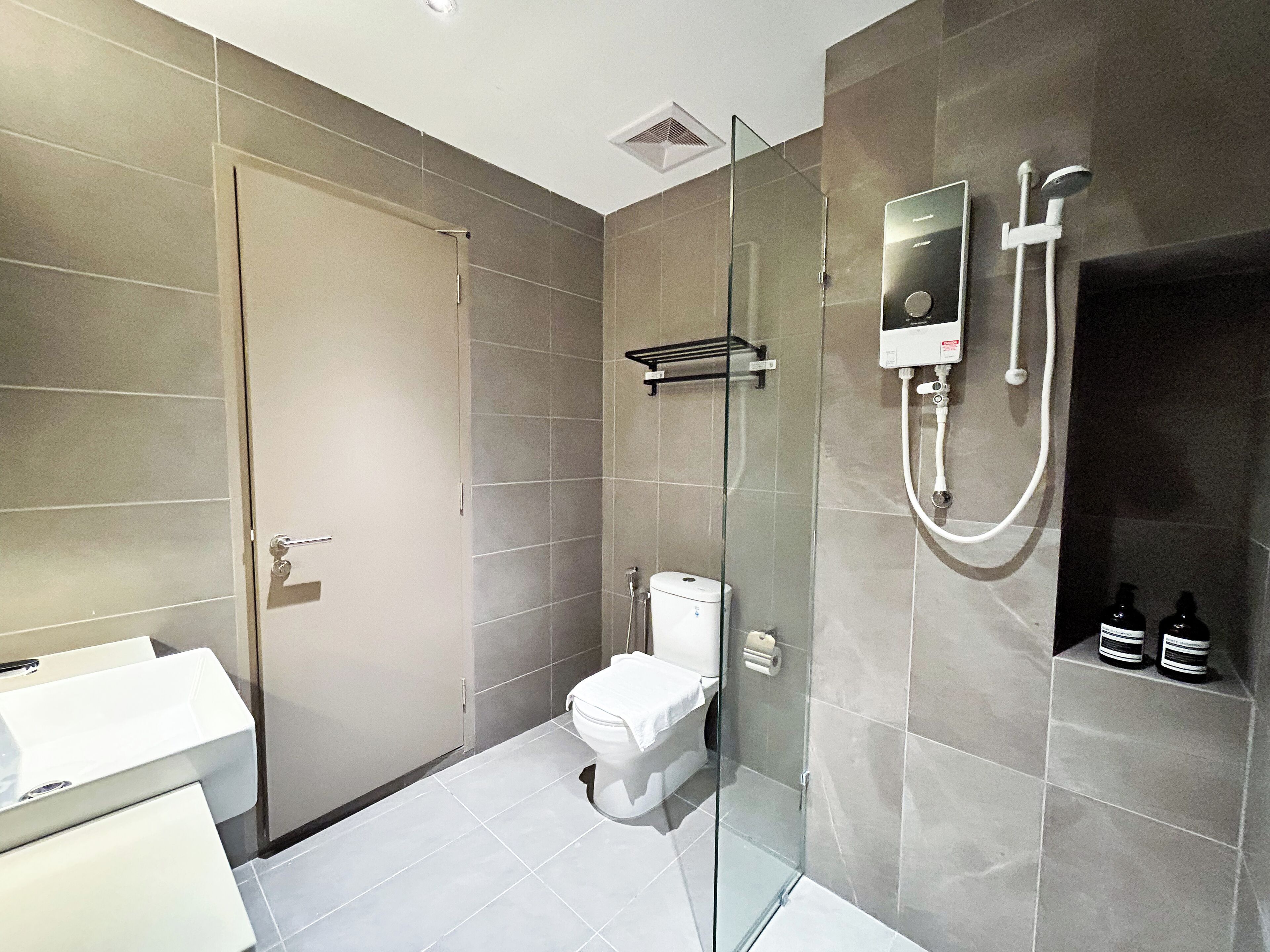 A modern bathroom with a glass-enclosed shower, a toilet, and a white sink.