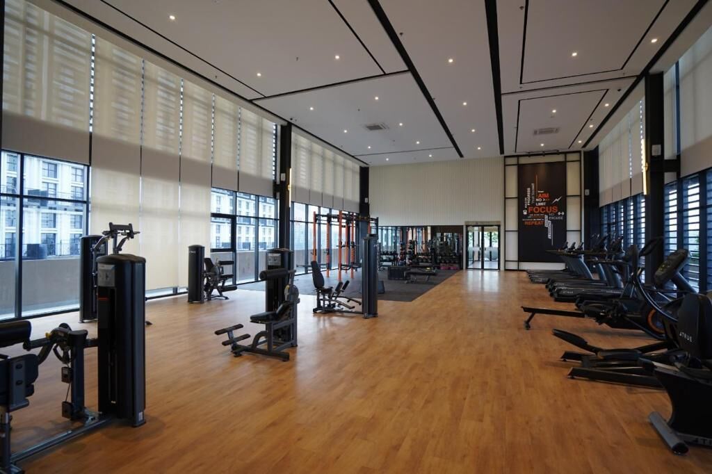 Una àmplia sala de gimnàstica amb màquines cardiovasculars, espais de musculació i una gran paret amb finestres que deixa entrar llum natural.