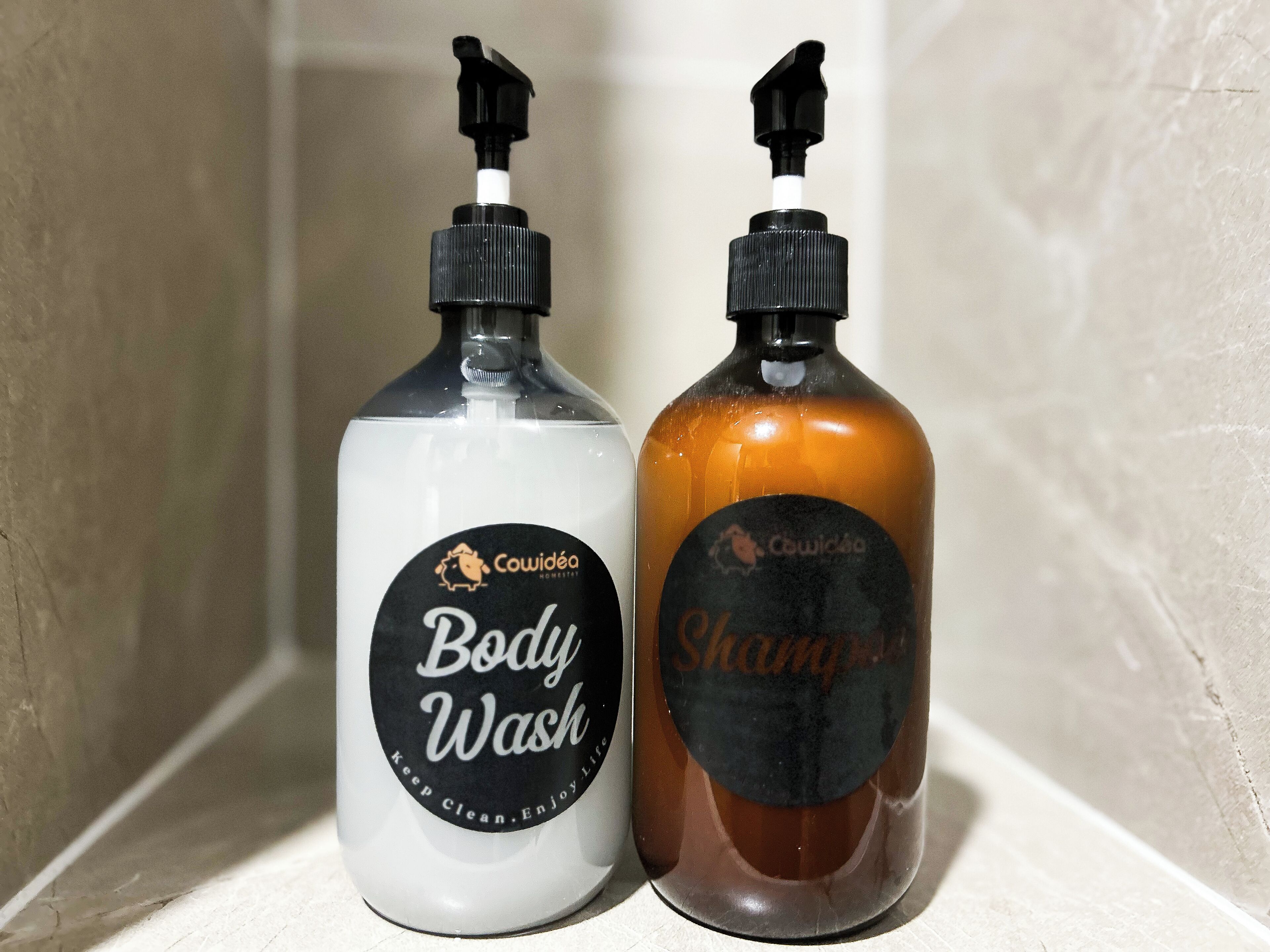 Deux bouteilles de gel douche et de shampoing Cowidée sur le comptoir d’une salle de bain.