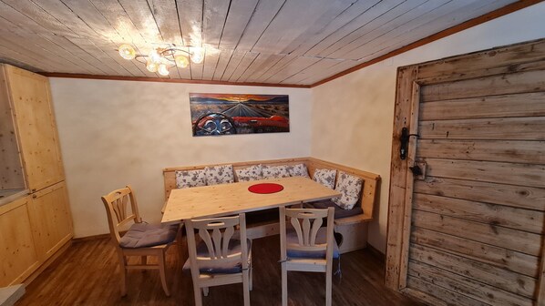 A cozy dining area with a wooden table, bench seating, and a painting of a car on the wall.