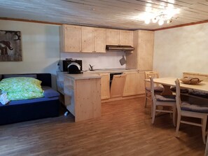 Une cuisine compacte avec des meubles en bois, un lave-vaisselle encastré et un coin repas comprenant une table et des chaises.