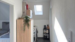 A narrow hallway with a kitchenette, a small window, and a bed visible on the left. - New! Exclusive city apartment - washing machine (Karlsruhe)