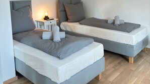 A modern bedroom with two beds, a nightstand, and a lamp. - New! Exclusive city apartment - washing machine (Karlsruhe)