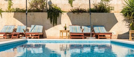 A pool area with lounge chairs and umbrellas.