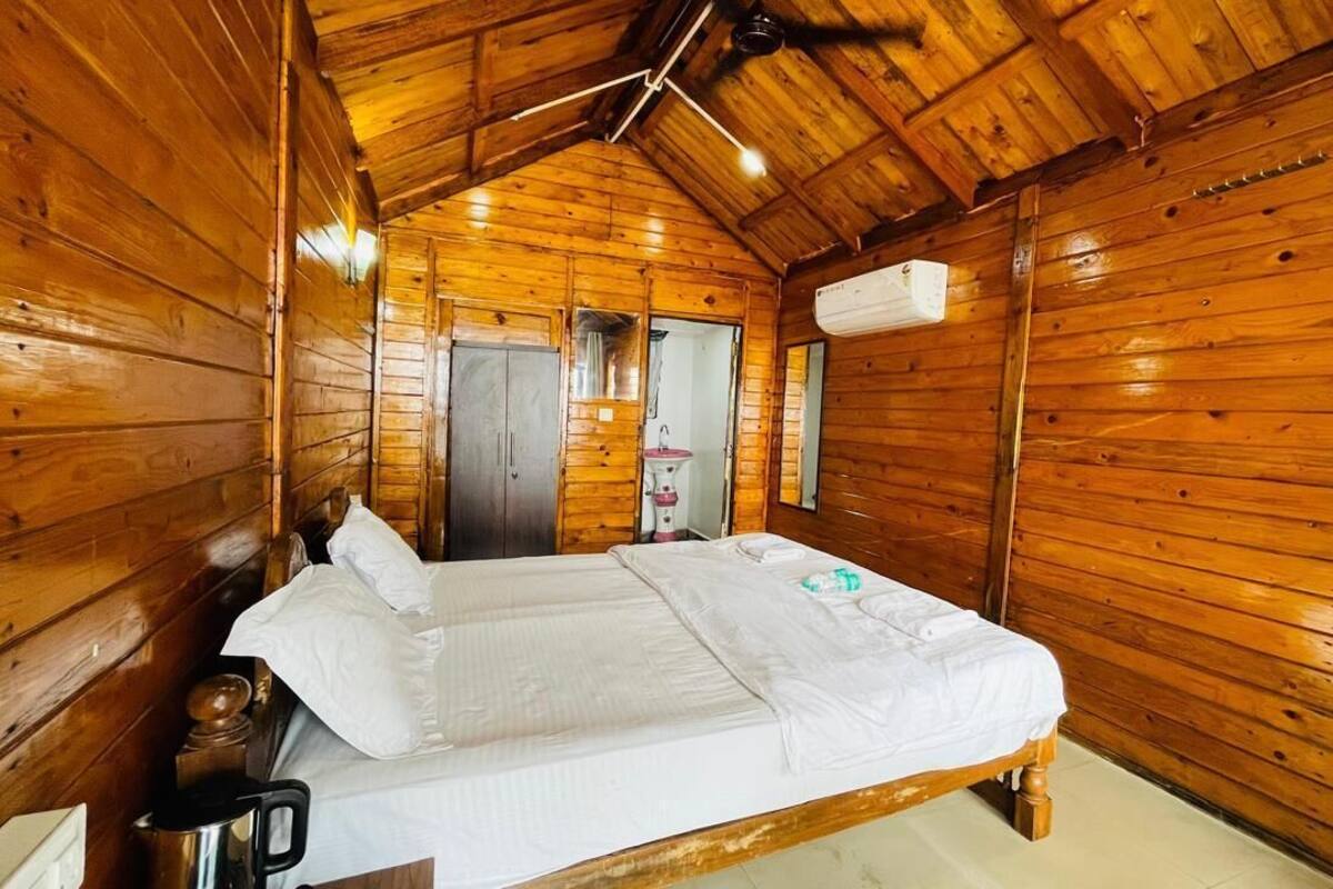 A wooden cabin room with a bed, a sink, and a ceiling fan.