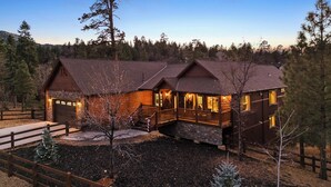 A log cabin with a stone foundation, a wooden deck, and a large porch.