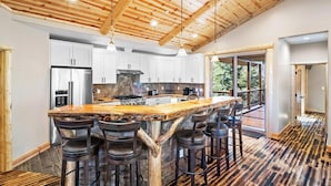 Una cocina amplia con una isla grande, armarios blancos y techo de madera.