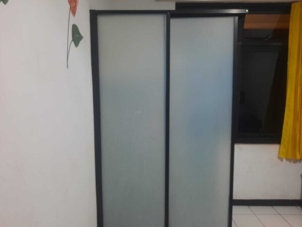 A room with a sliding door, a window with a yellow curtain, and a wall with a green leaf decoration. - Capital O 94419 Fresh Hotel (Tasikmalaya)