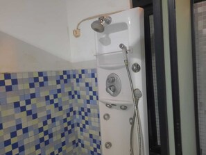 Une douche équipée d’un pommeau de douche à main et d’un robinet fixé au mur.