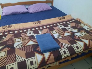 Un lit avec une couvre-lit à motifs, deux oreillers et une serviette bleue pliée.