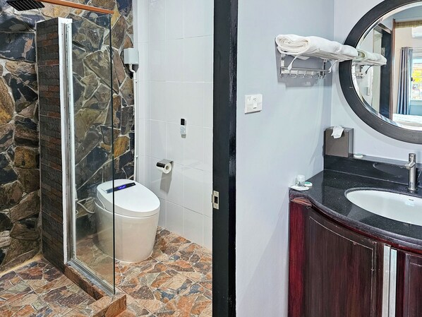 A bathroom with a glass-enclosed shower, a toilet, a sink with a mirror, and a towel rack. - The Son Resort (Pranburi)
