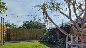 A backyard with a wooden fence, a lawn, and string lights.