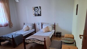 Een kamer met twee eenpersoonsbedden, een tafeltje, een stoel en een schilderij aan de muur.