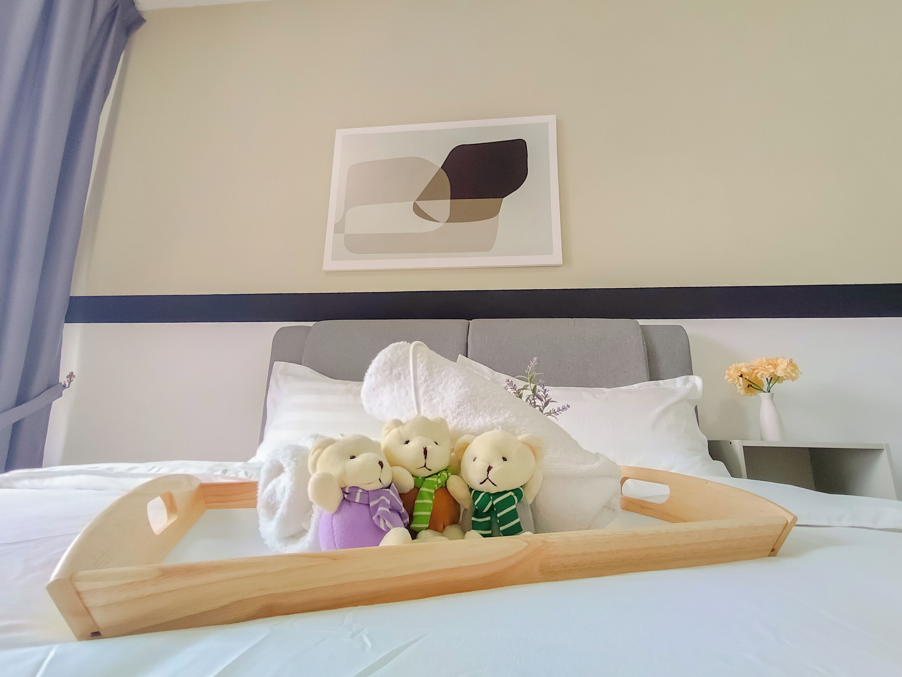 Un lit bien fait, avec un plateau en bois, des oreillers et trois peluches.