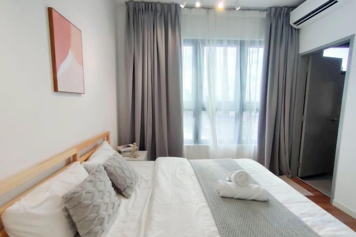 Een hotelkamer met een bed, nachtkastje, raam met gordijnen en een deur.