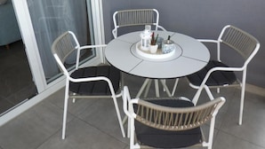 A round table with white chairs, a small potted plant, and a candle holder. - Cozy Apartment Bili (Privlaka)
