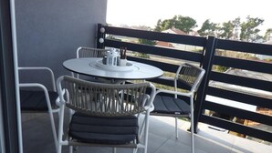 A balcony with a round table and two wicker chairs. - Cozy Apartment Bili (Privlaka)