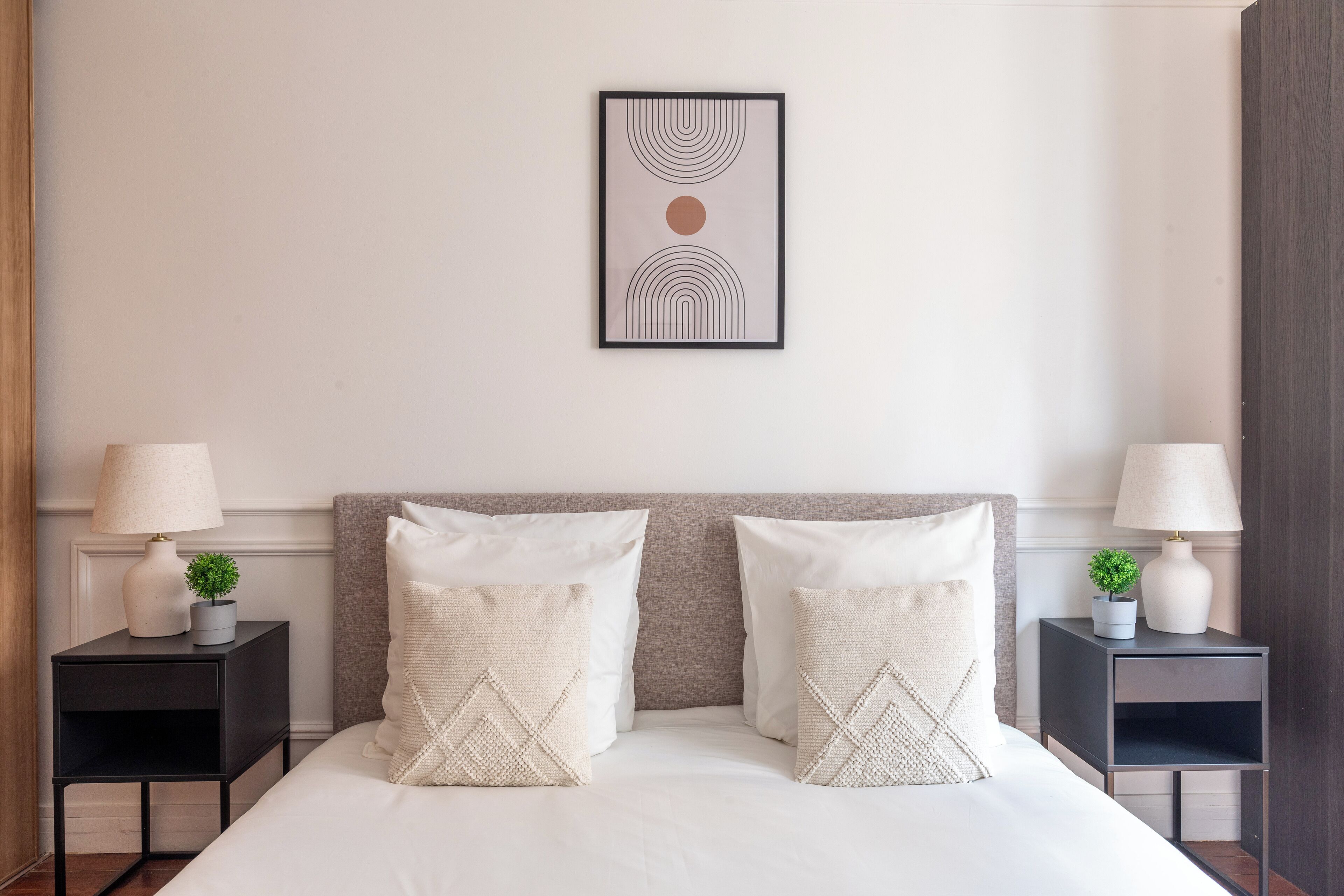 Una camera da letto ordinata con un letto grande, due comodini con lampade e un quadro appeso alla parete.