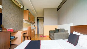 A hotel room with a bed, a desk, a sofa, and a kitchenette. - Collection O Apartment By Boboin Baros Near Stasiun Cimahi (Cimahi)