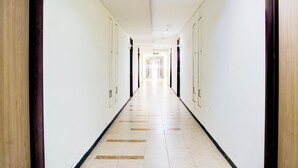 A long, narrow hotel corridor with doors on both sides and a tiled floor. - Collection O Apartment By Boboin Baros Near Stasiun Cimahi (Cimahi)