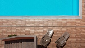 Una piscina con due sdraio e un muro in pietra.