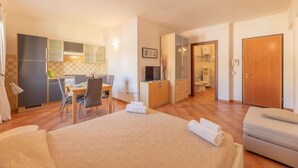 Una camera d'albergo con un letto, una scrivania, una sedia, angolo cottura e bagno.