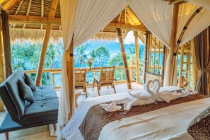 A room with a bed, a sofa, and a view of the outdoors. - Ayo Hill Villa (Sidemen)