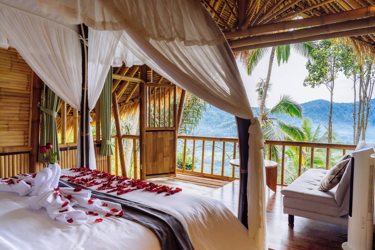 A bedroom with a bed, a balcony, and a view of the mountains.