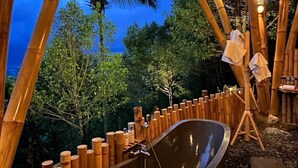 A bamboo structure with a large bathtub and an easel with a painting.
