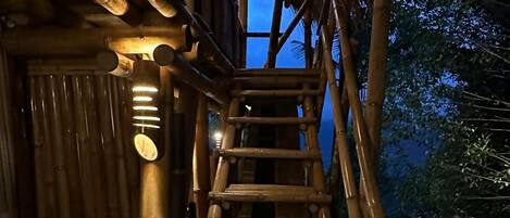 Una escalera de bambú que lleva a un edificio con techo de paja.