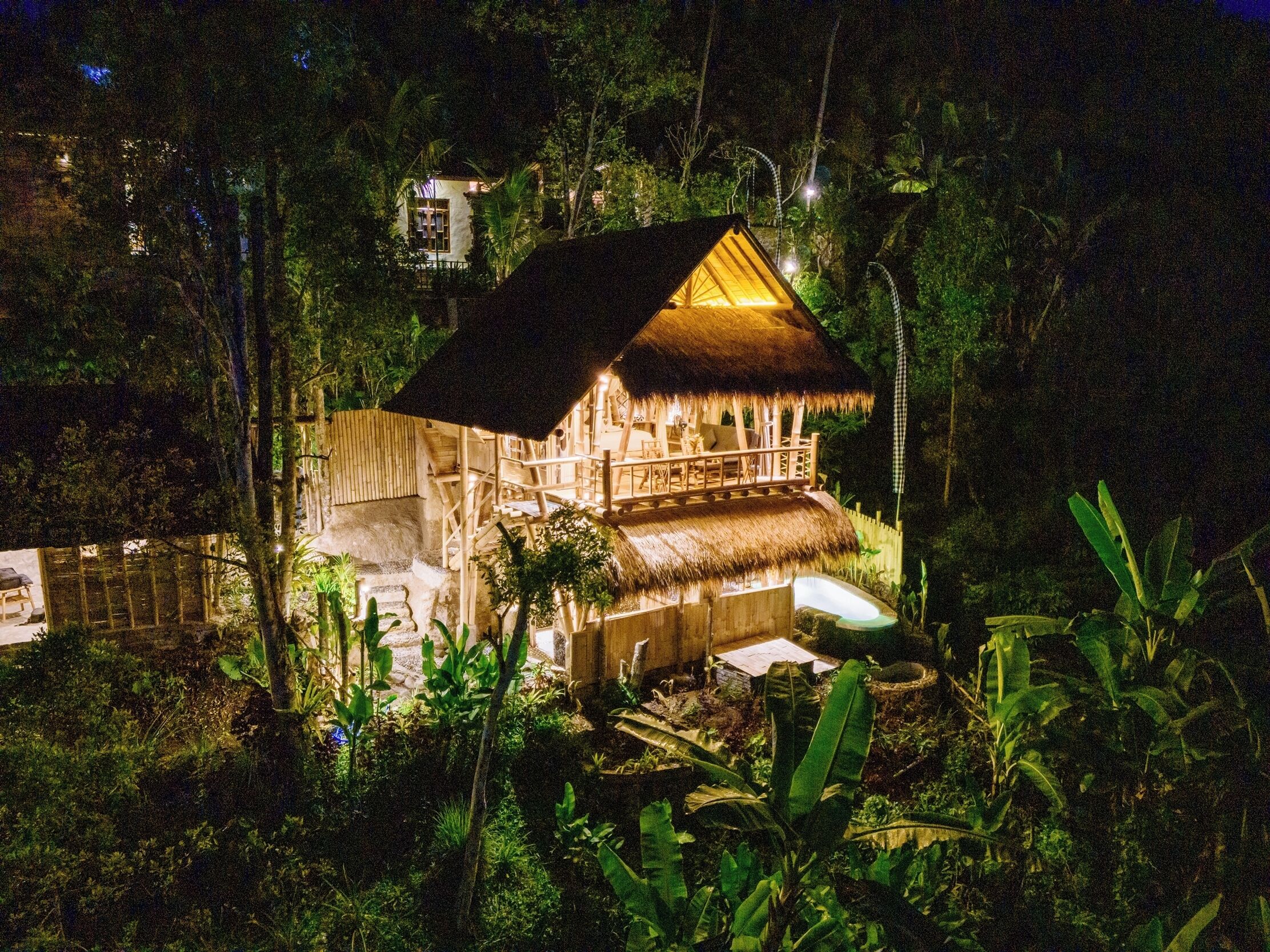 A wooden structure with a thatched roof, surrounded by dense vegetation.
