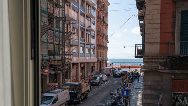 Une vue de rue avec des véhicules garés, des bâtiments et une vue sur la mer.