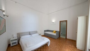 Une chambre à coucher avec un lit, des tables de chevet, un canapé gris et une armoire.