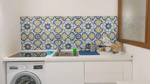 A compact kitchen with a washing machine, a sink, and a tiled backsplash. - Arcoleo Prestige 2 By Dimorra (NAPOLI)